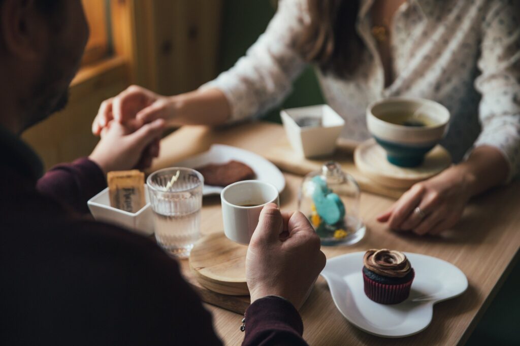 homem segura a mão da namorada em mesa de café durante encontro