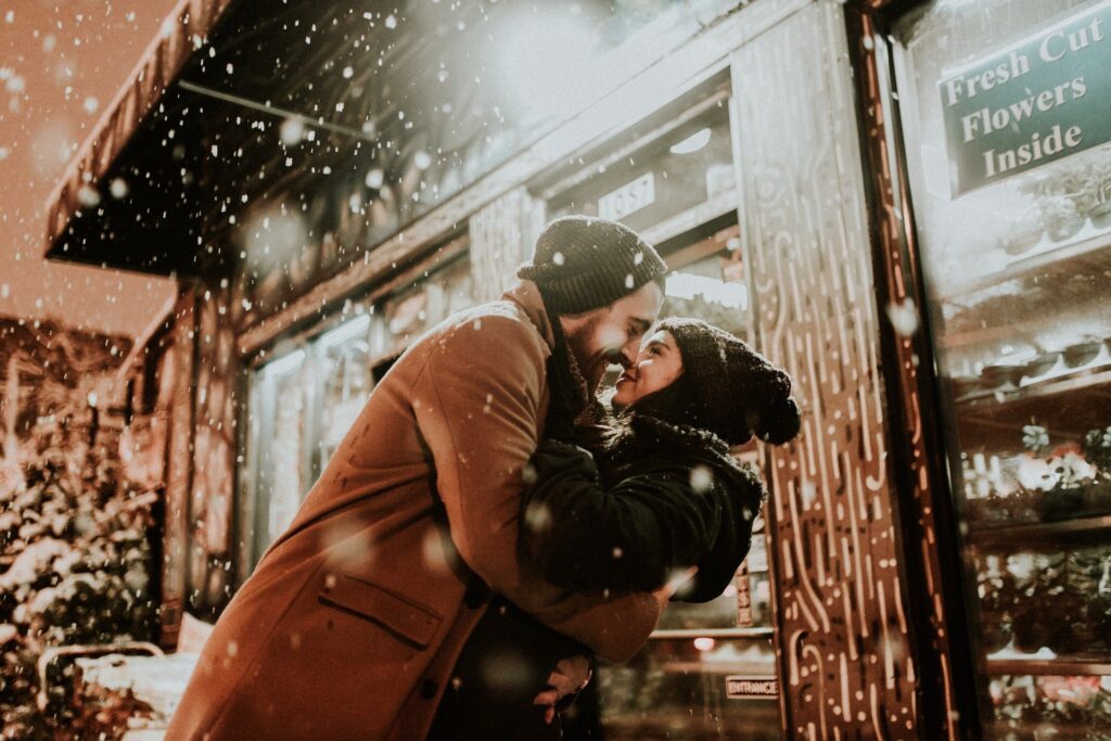 casal se beija de forma romântica na durante queda de neve suave