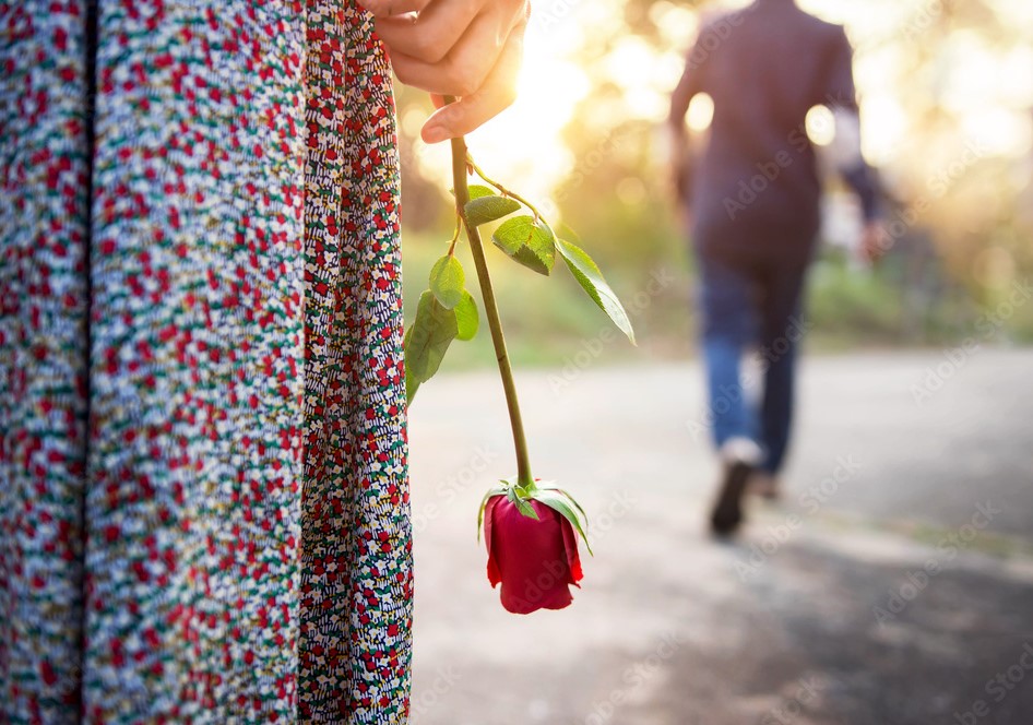 Mulher parada segurando uma rosa enquanto homem vai embora em sua frente