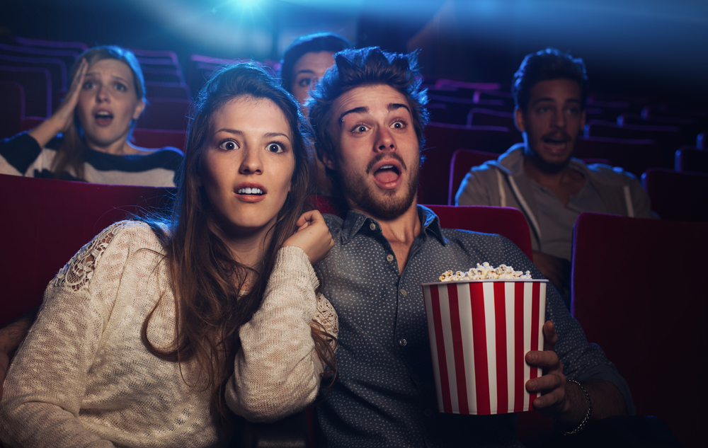 Casal no cinema com semblante de assustados