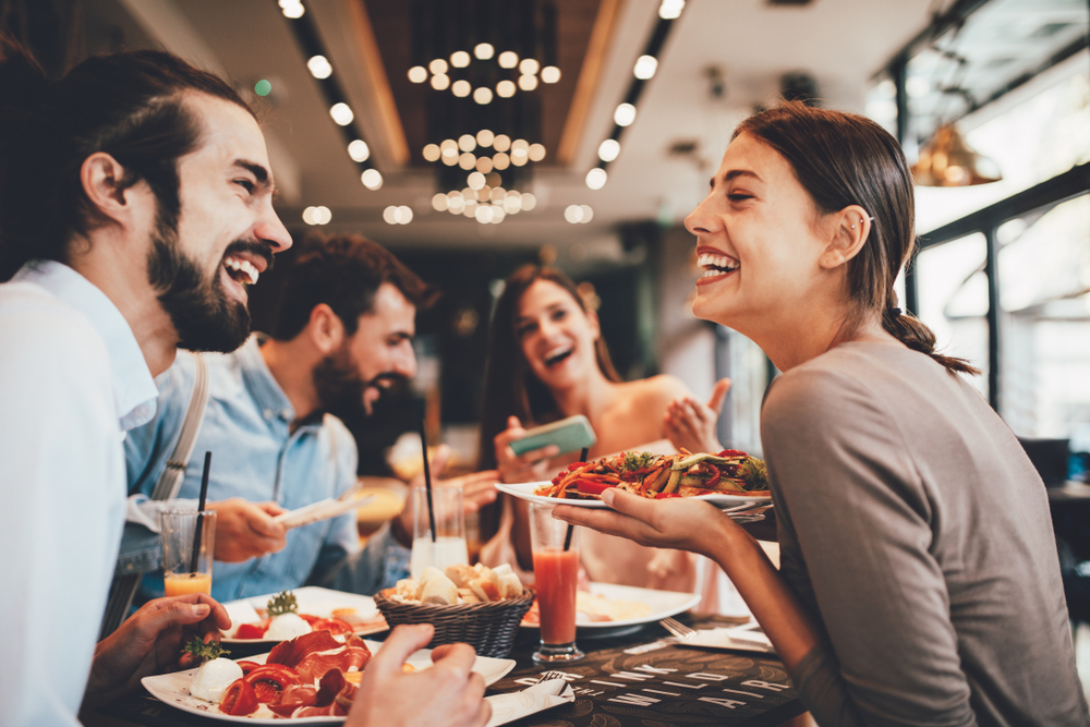 Dois casais em uma mesa farta de alimentos felizes