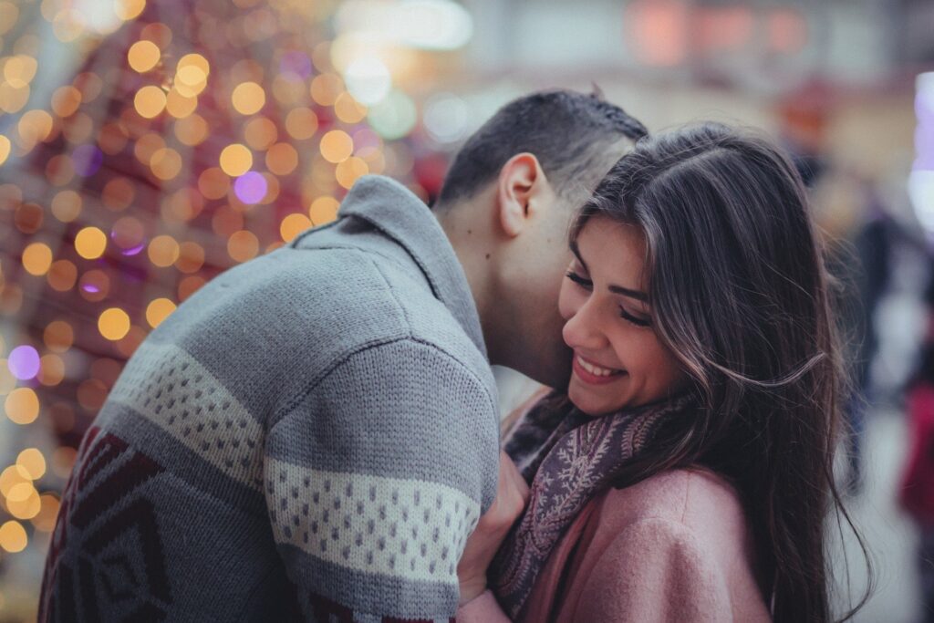 mulher sorri enquanto recebe beijo no rosto de um homem