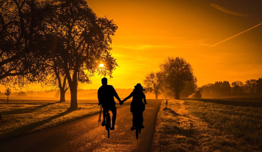 casal andando de bicicleta juntos ao pôr do sol