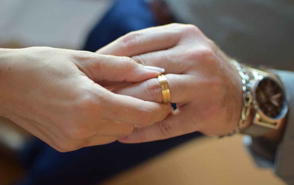 mulher segura a mão de homem usando aliança de casamento
