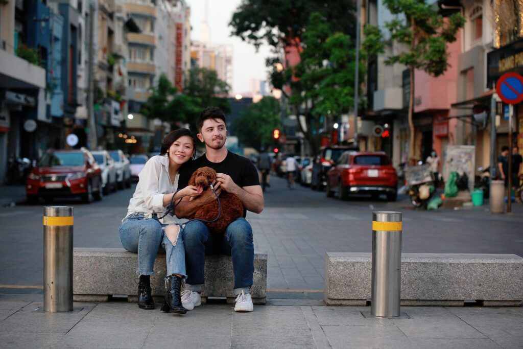 casal ouve música juntos com fone de ouvido sentados em banco na rua, e seguram um cachorro