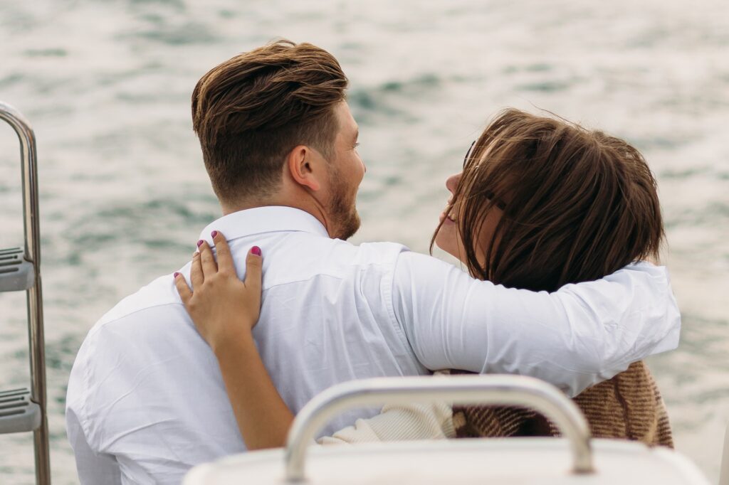 casal abraçado, de costas para a câmera, em barco