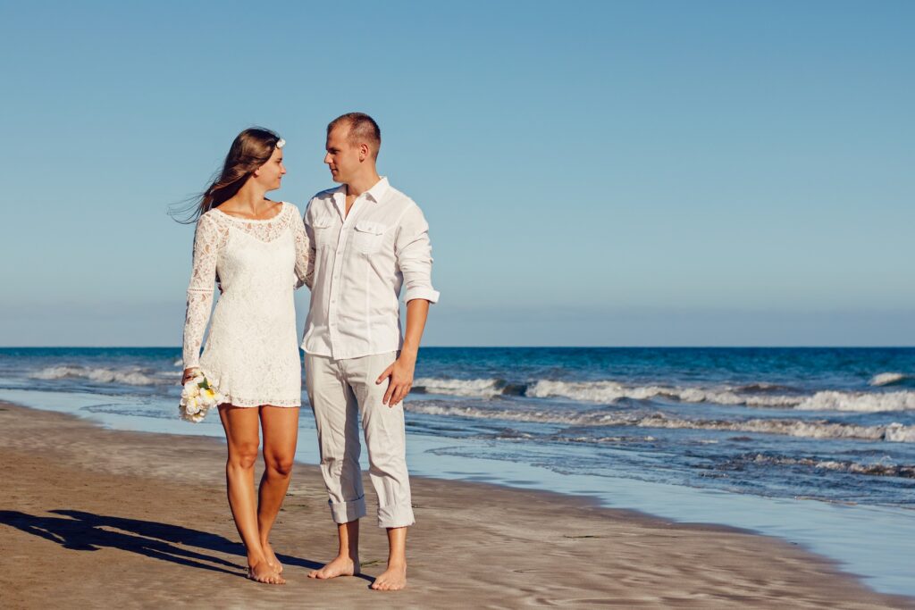 casal caminhando na praia e se olhando nos olhos