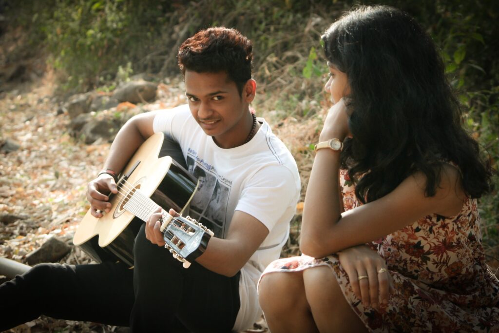 homem tocando violão na companhia da namorada, ao ar livre