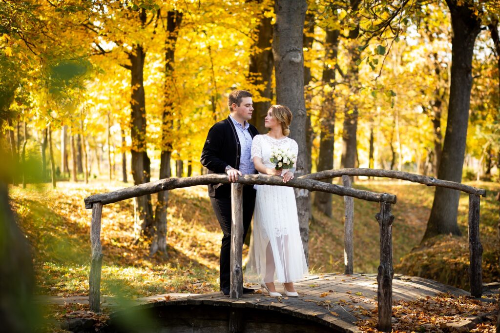 casal passeando no bosque cruzando uma ponte, mulher segura um buquê de flores