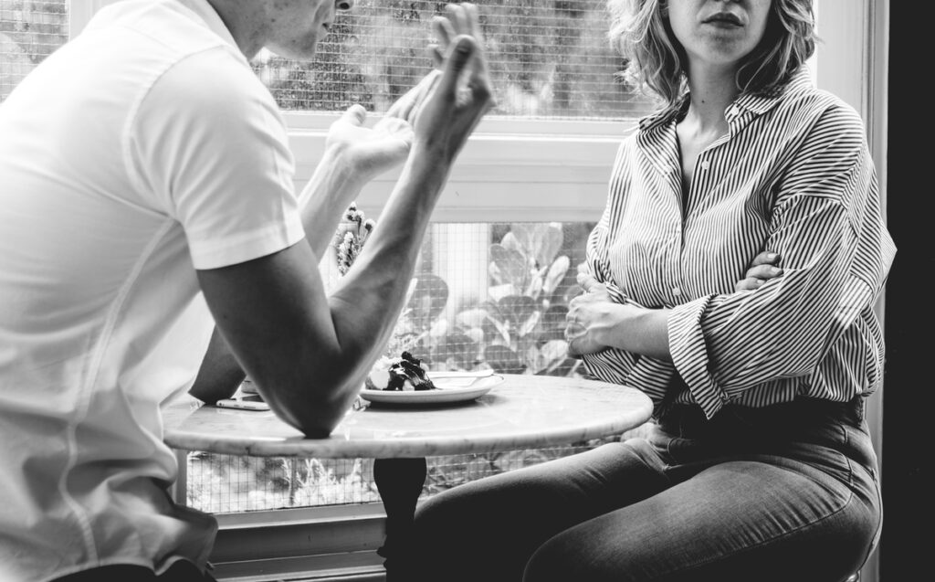 casal sentado a mesa e conversando chateados