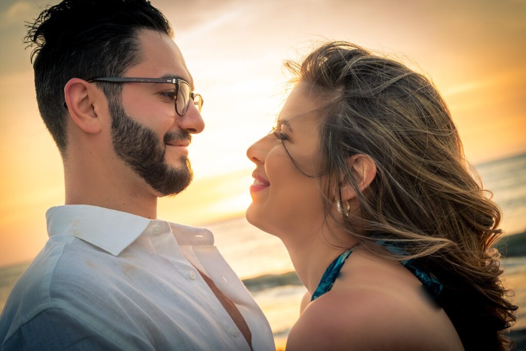 casal se olha nos olhos na praia durante nascer do sol