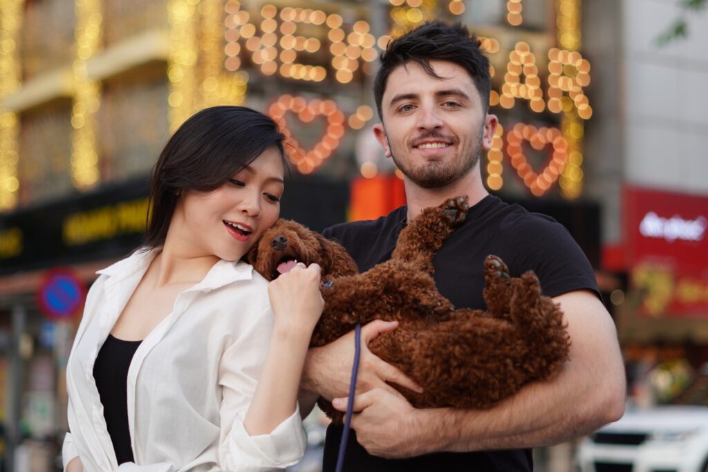 homem segura cachorro no colo enquanto mulher brinca com ele