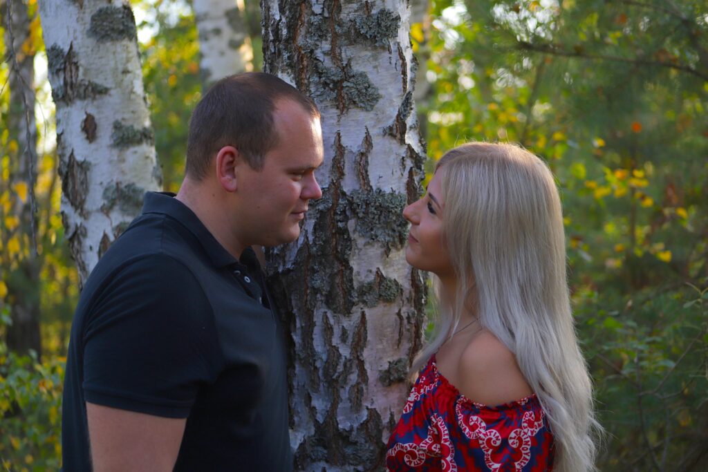 casal se olha frente a frente diante de bétula em bosque