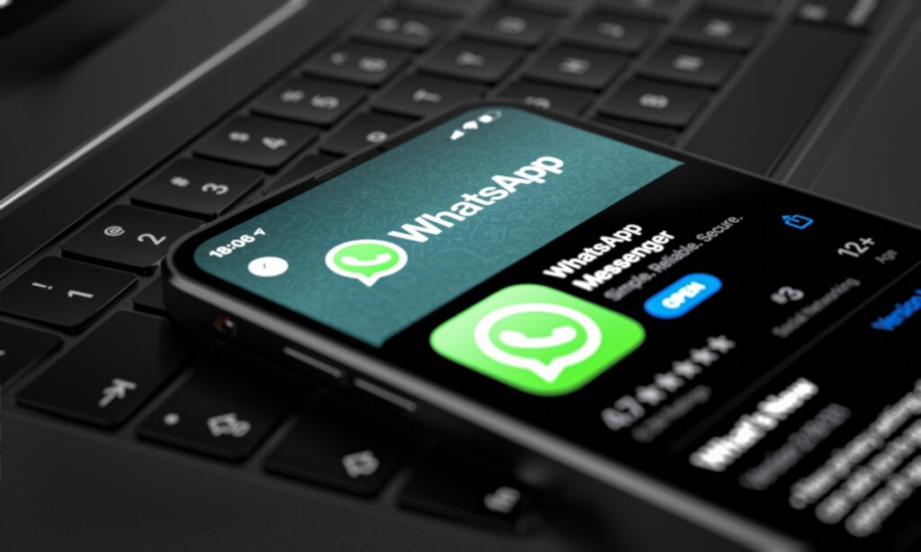 celular exibindo ícone e botão do whatsapp sobre teclado de computador